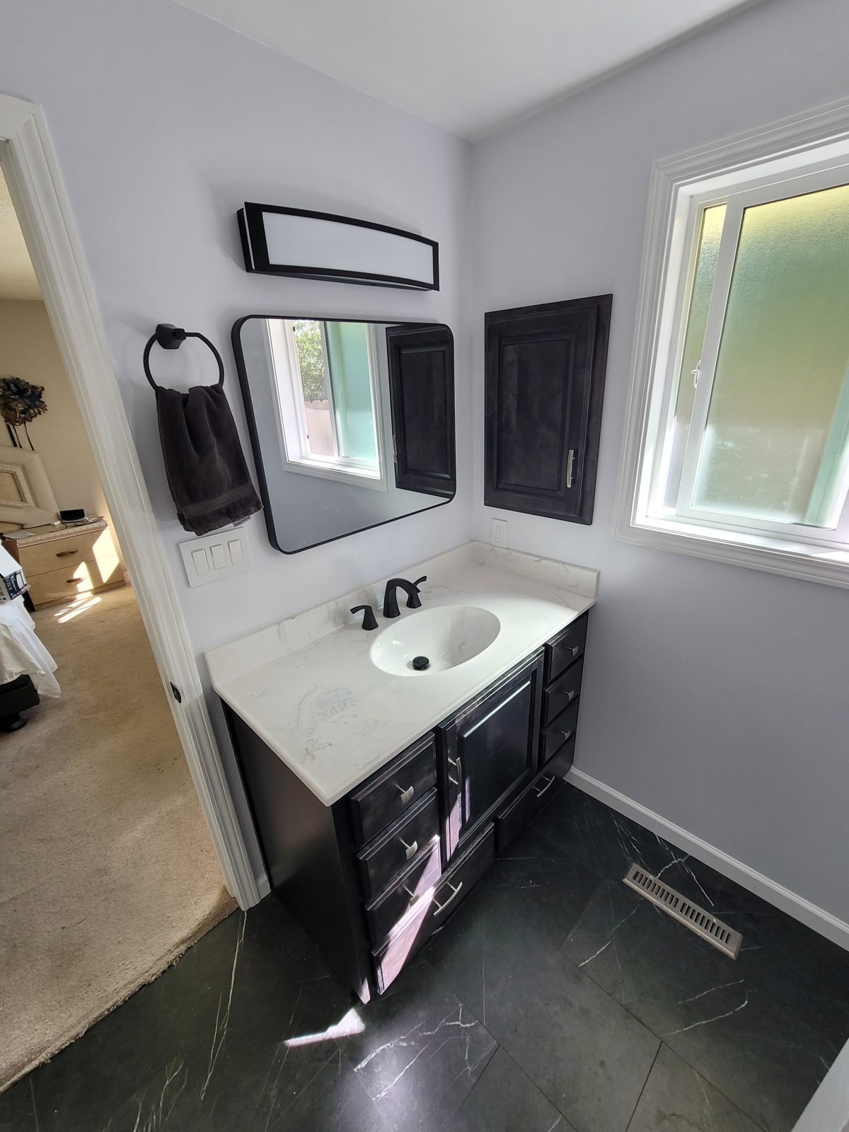 Bathroom vanity and white sink beside a window