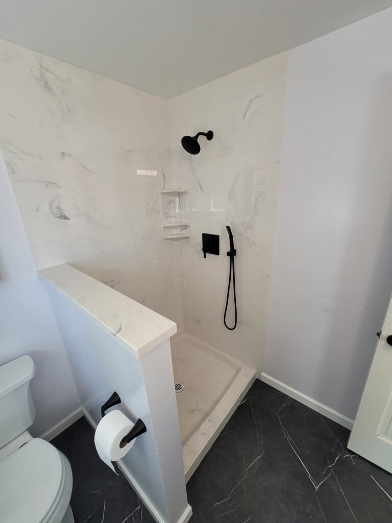 White shower enclosure with dark fixtures and tile flooring