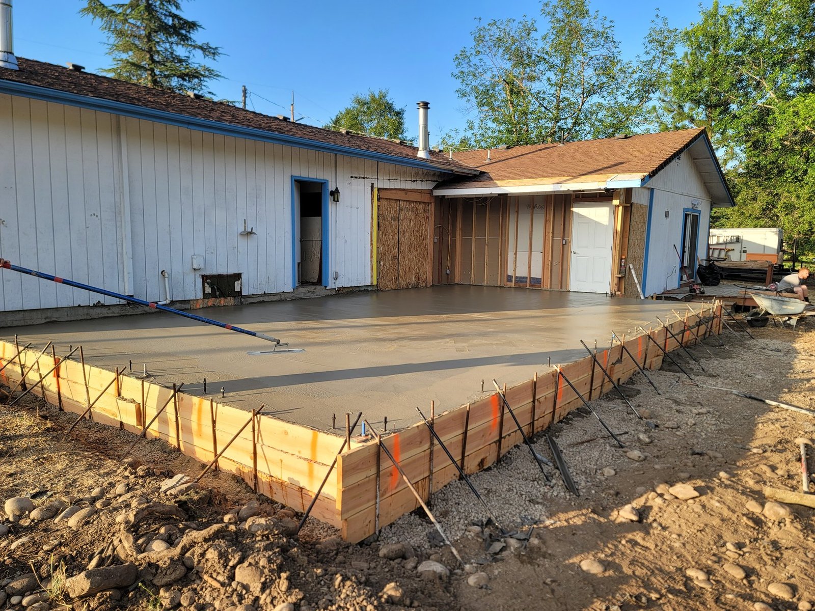 Fresh concrete slab and forms beside an outbuilding