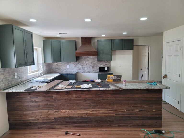 Green kitchen cabinets and wood peninsula during installation