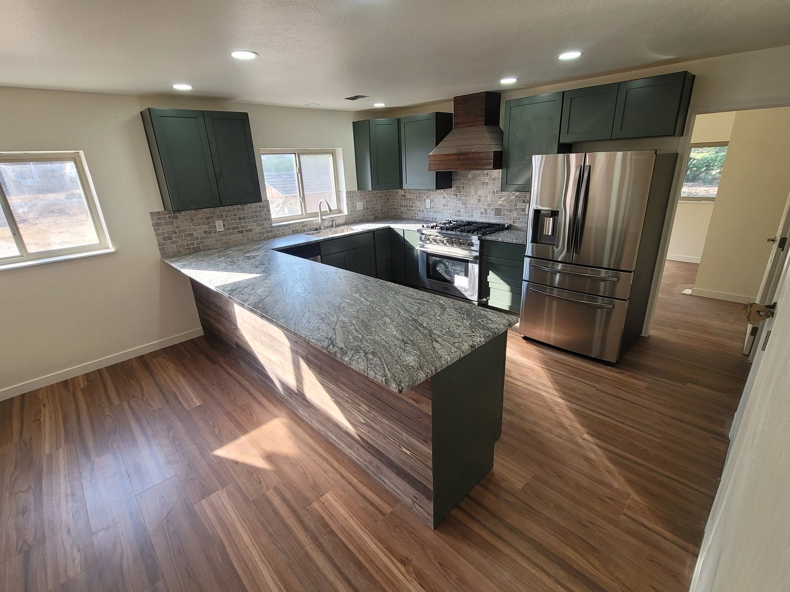 Green kitchen cabinets and dark peninsula counter