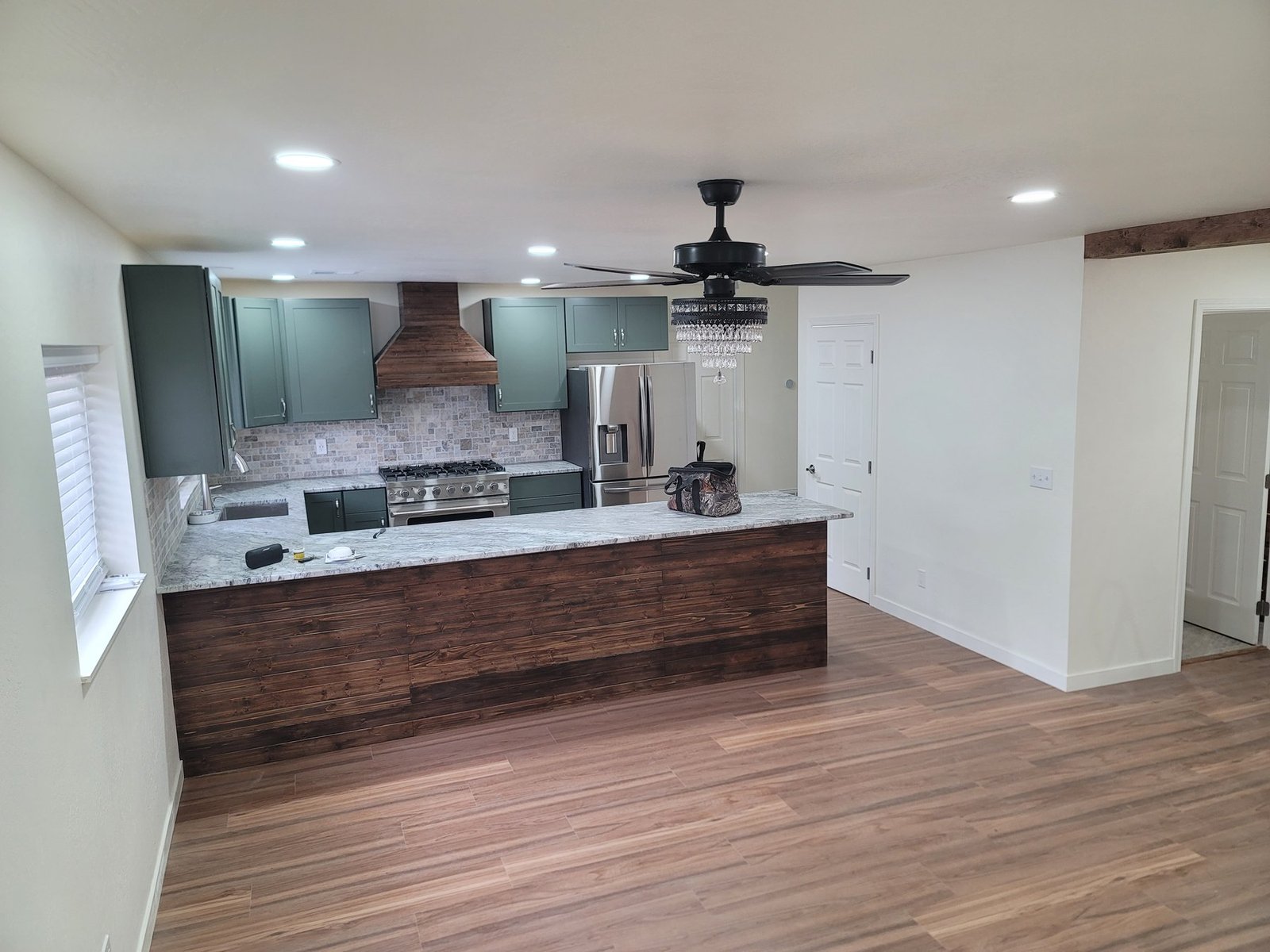 Green kitchen with wood peninsula and open floor space
