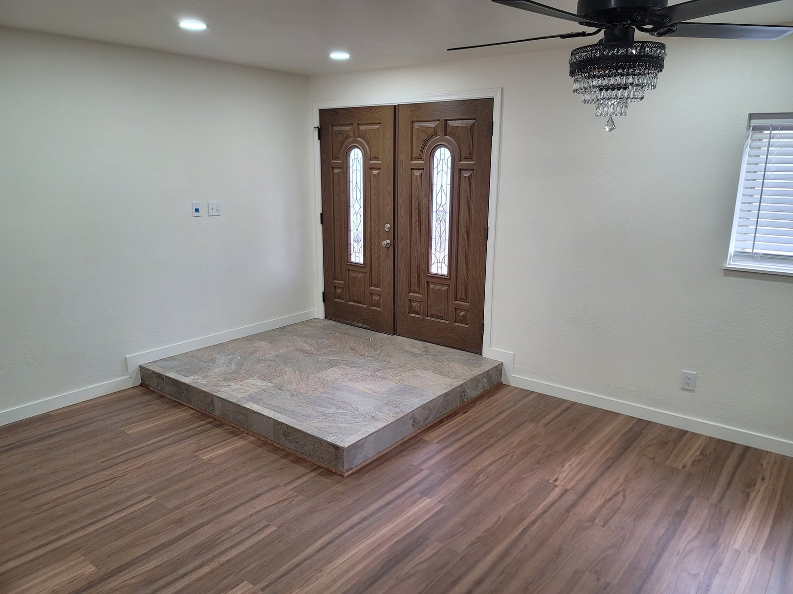 Double wood entry doors and a raised tile landing