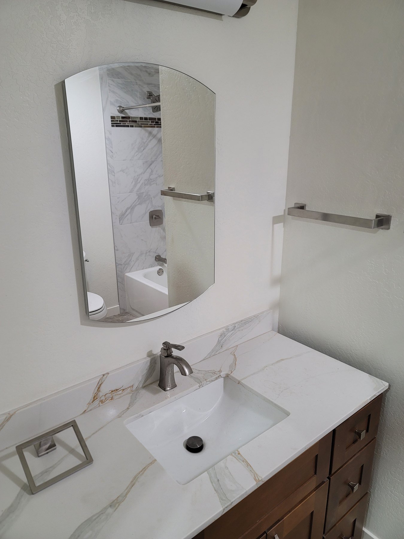 Bathroom vanity with a white counter, mirror, and tile surround