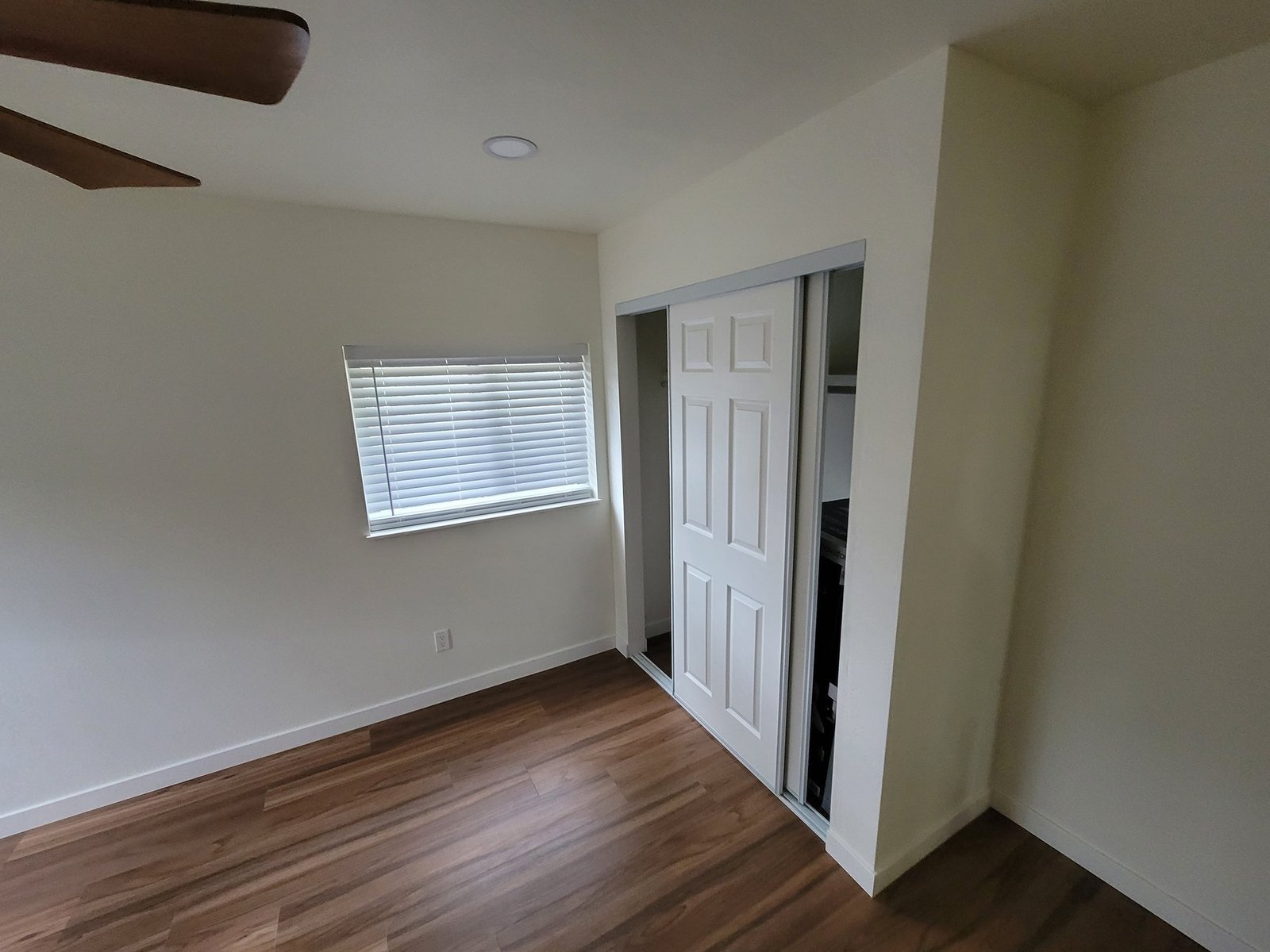 Bedroom flooring beside a window and closet doors